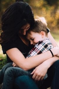 Woman wrapping her arms around a male child.