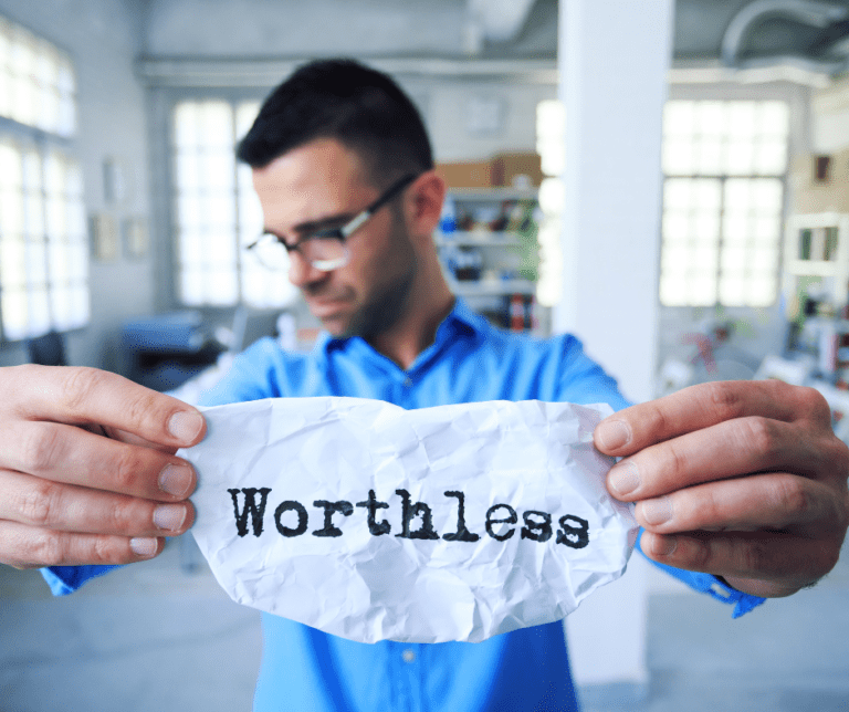 Man holding a crumpled paper with 'Worthless,' a reminder for estate planning in Michigan with 5 West Legal Services.