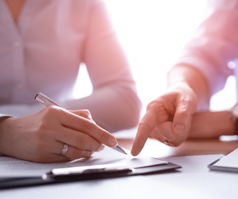 two people, one pointing at something another is holding a pen to